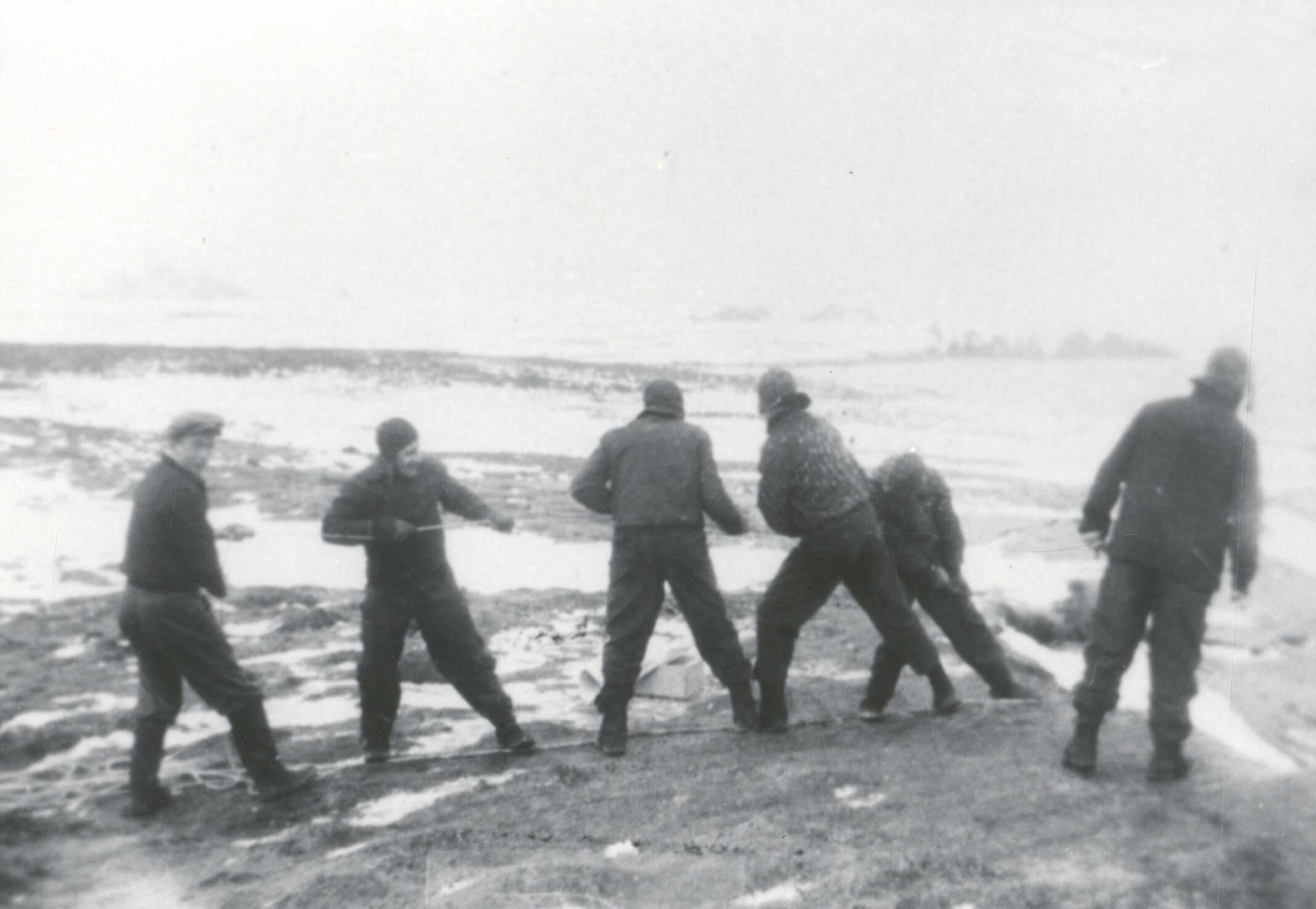photo of men dragging bodies up cliffs